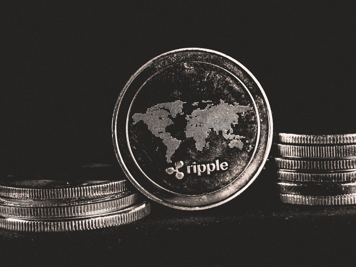 리플(XRP) 로고가 새겨진 은색 동전이 세계지도 무늬와 함께 놓여 있다