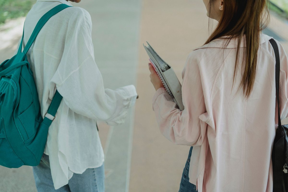 책과 가방을 든 학생들이 캠퍼스를 걷는 뒷모습